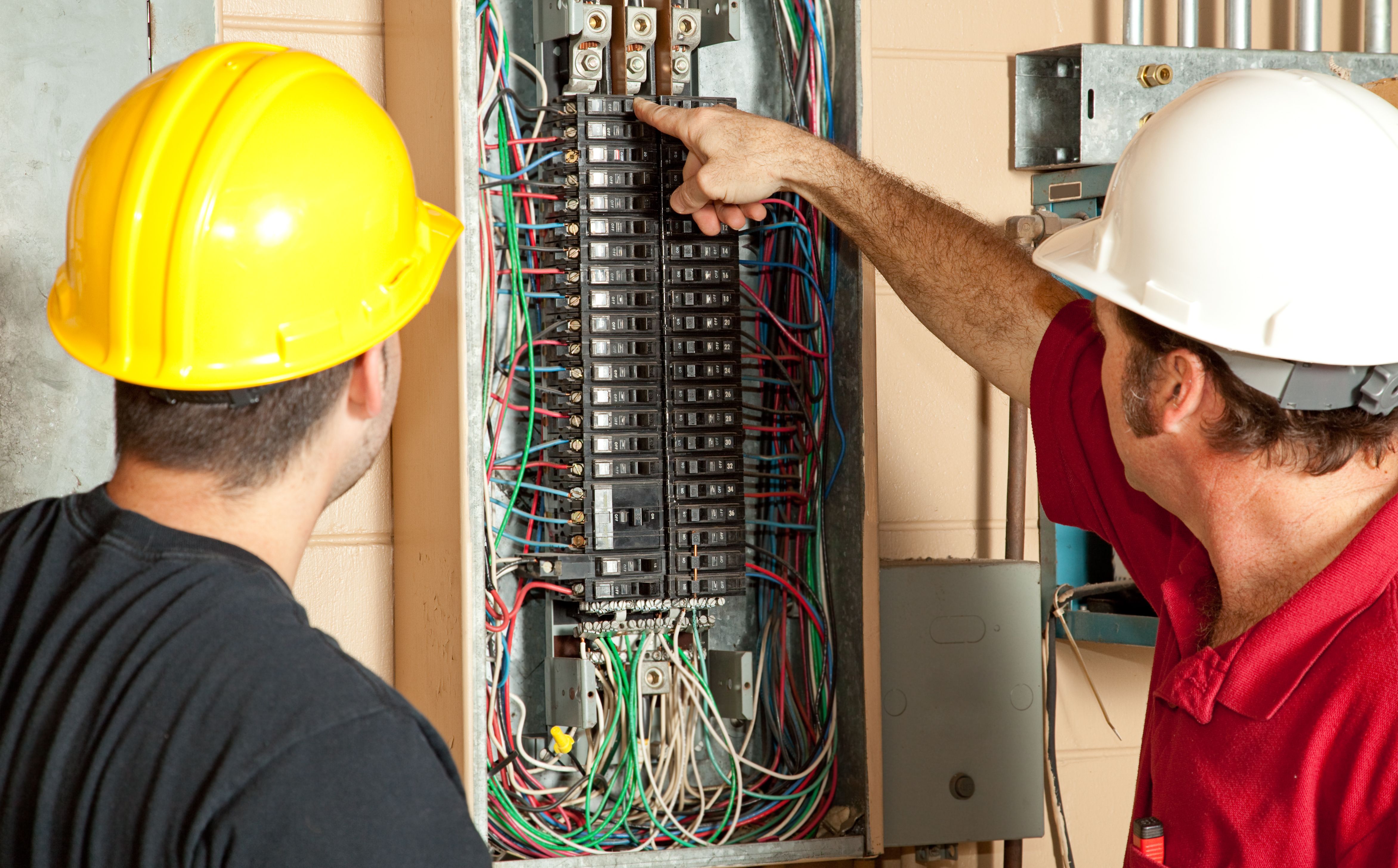 two electricians while one is pointing on panel